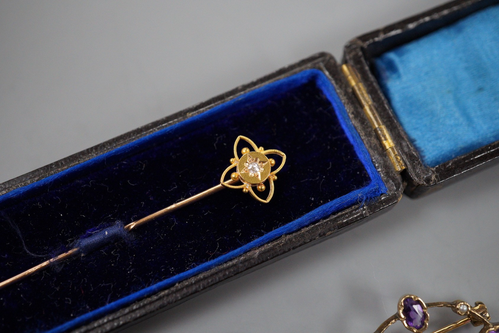 An early 20th century yellow metal, amethyst and seed pearl set oval brooch, 28mm, a Victorian yellow metal mourning brooch, a similar yellow metal and diamond set stick pin, a white metal and enamel fob watch(a.f.) and